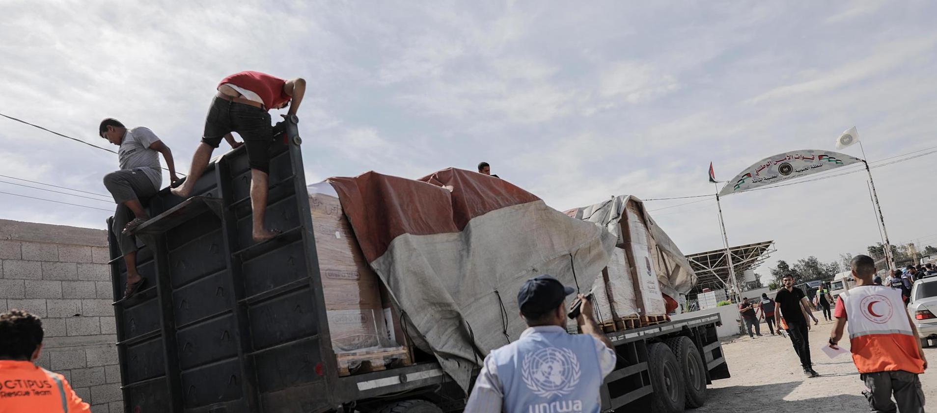 Funcionarios de la Media Luna Roja palestina ayudan a descargar la ayuda para la Franja de Gaza