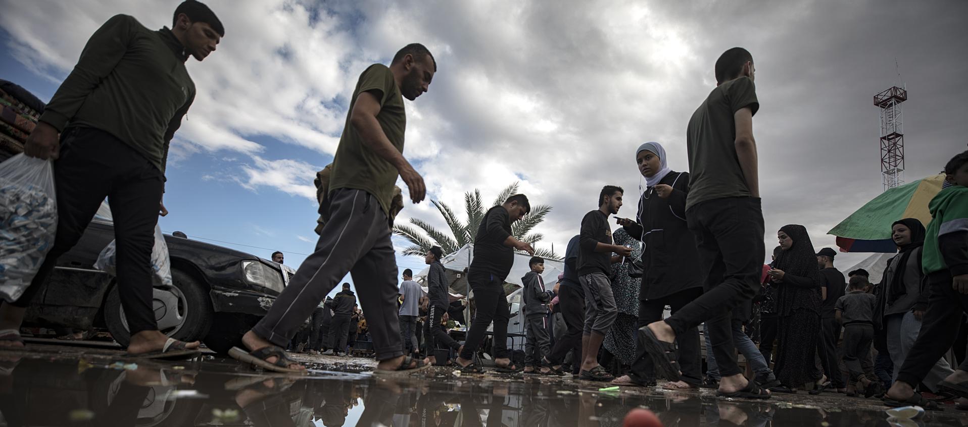 Los palestinos pasan junto a un charco de agua después de una noche lluviosa.