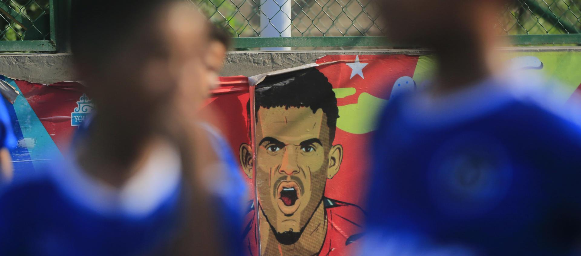 Jóvenes de escuela de fútbol entrenan en Barrancas y al fondo una retrato de Luis Díaz. 