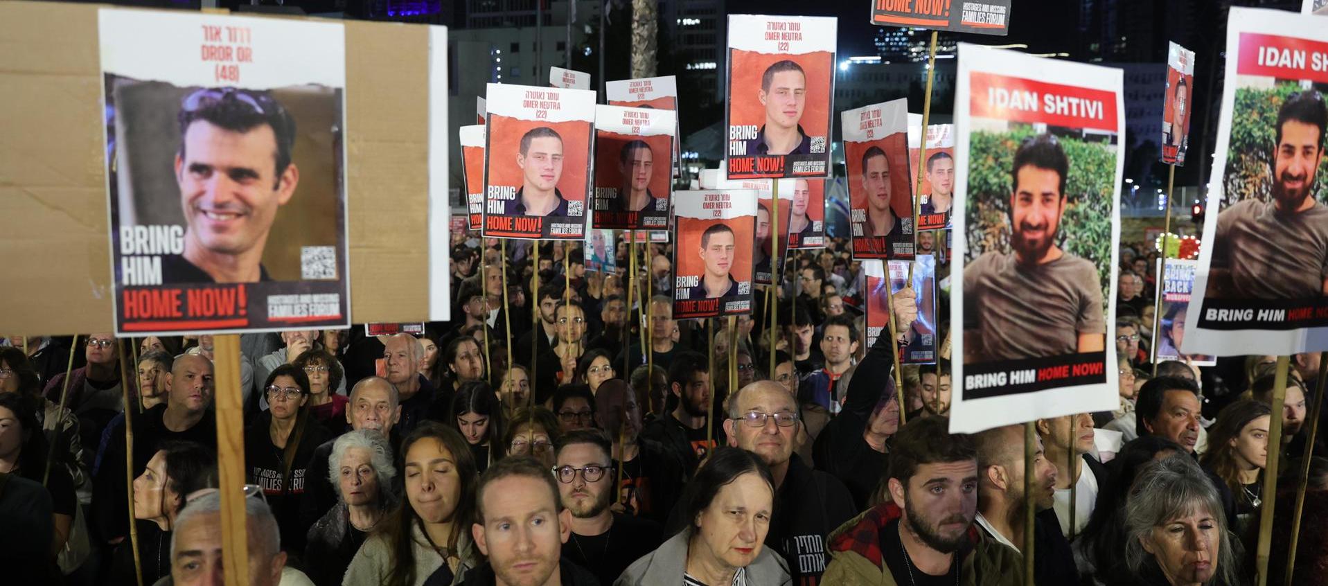 Simpatizantes y familiares sostienen fotografías de rehenes retenidos por Hamás en Gaza mientras participan en una manifestación pidiendo su liberación. 