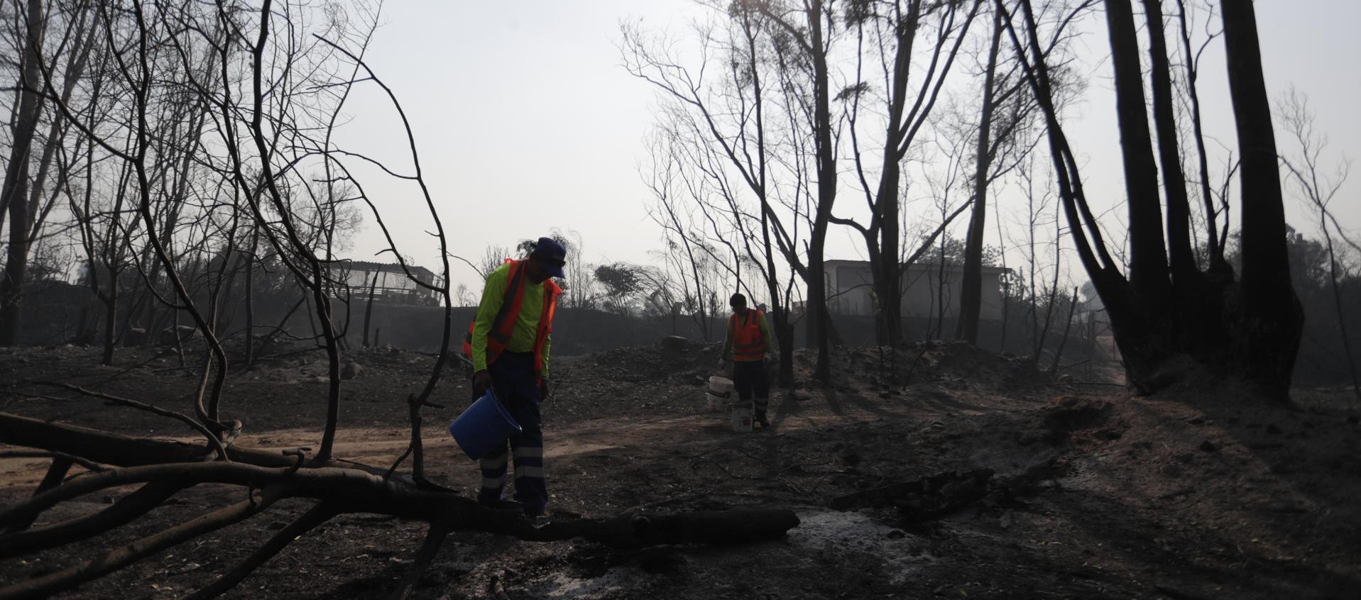 Bomberos y voluntarios tratan de extinguir los focos de un incendio en la zona de Patagual, en Viña del Mar. 