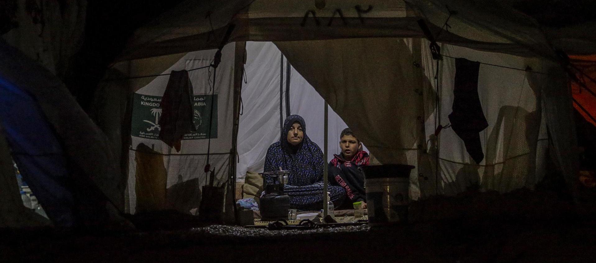Una mujer palestina y su hijo que huyeron con su familia del norte de la Franja de Gaza se sientan dentro de su refugio en Deir al Balah, sur de la Franja de Gaza