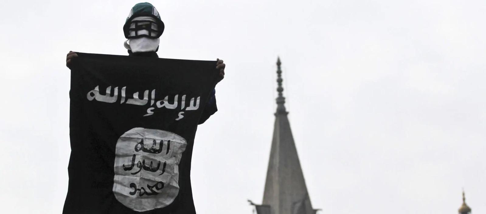 Hombre sostiene la bandera del Estado Islámico.
