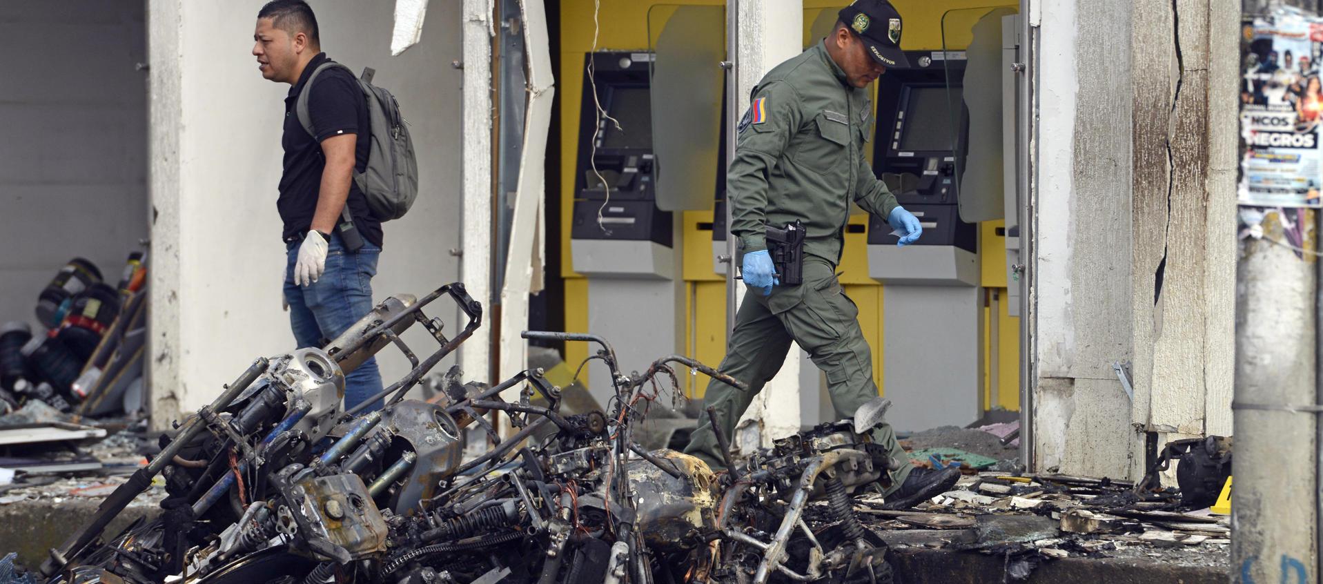 Uniformados caminan sobre los destrozos tras el atentado con motocicleta bomba en una estación de Policía en Jamundí
