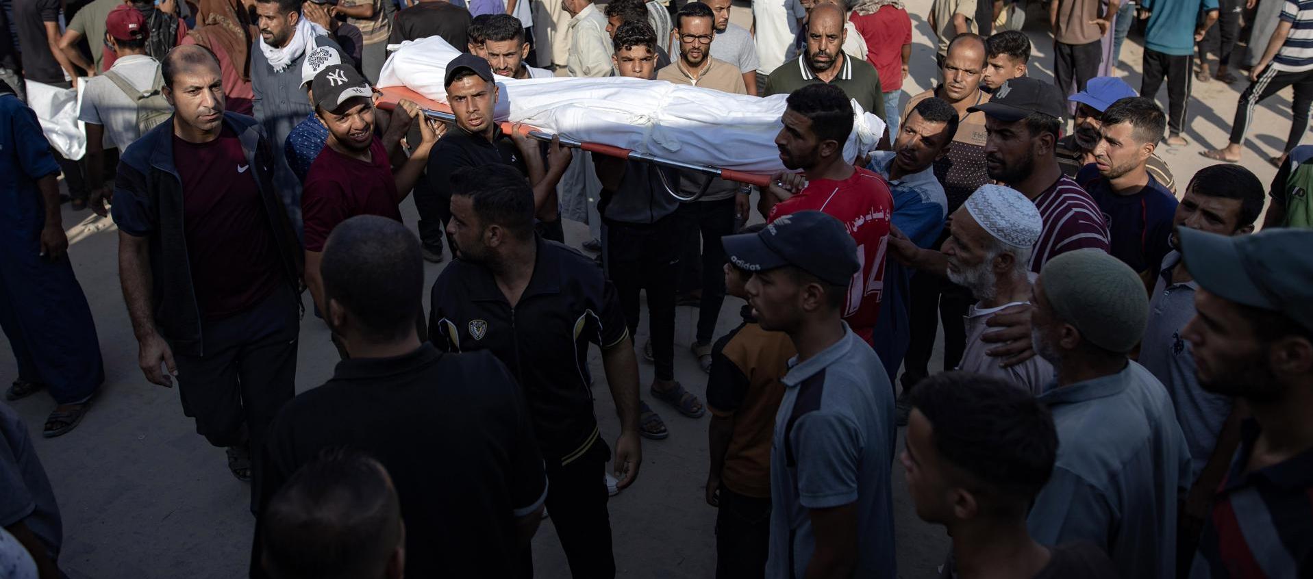 Palestinos levantan el cadáver de uno de los fallecidos.