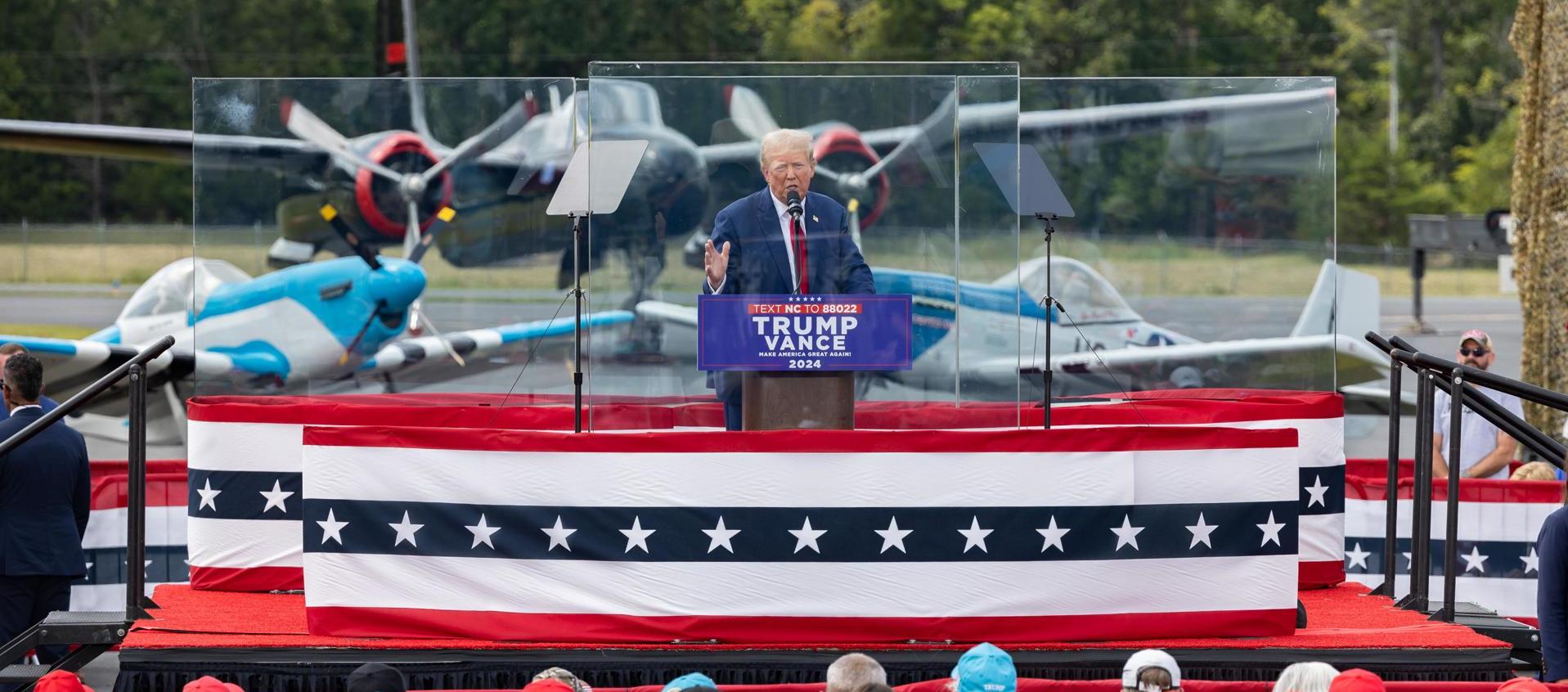 Donald Trump ofreciendo un discurso protegido con vidrios antibalas. 