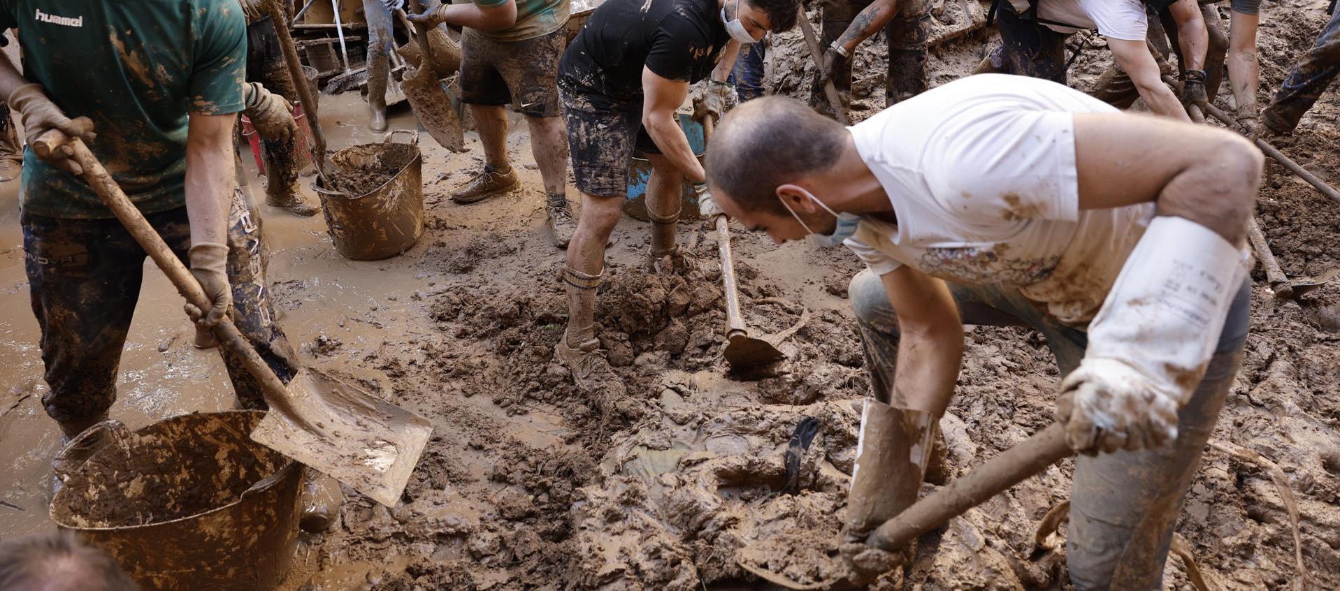 Personas retiran el lodo acumulado en una calle de Paiporta.
