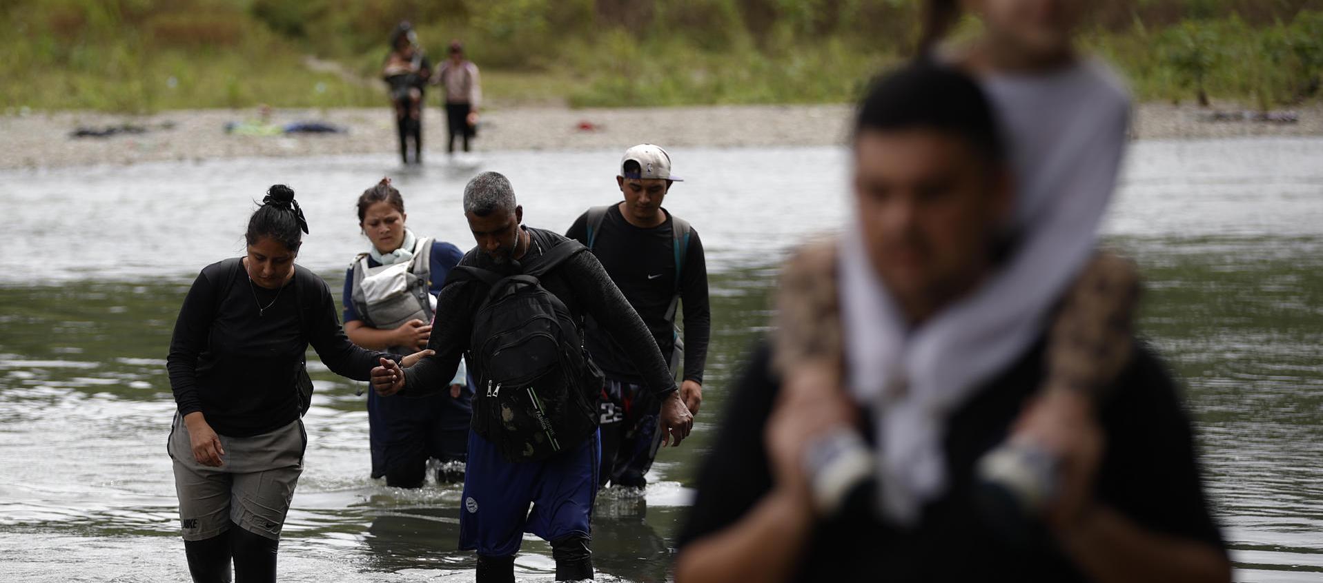 Migrantes cruzando el río Tuquesa luego de atravesar la selva del Darién, en Panamá.