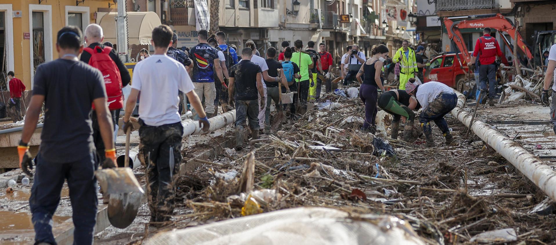 Decenas de personas tratan de retirar todo lo acumulado en uno de los puentes de Paiporta, Valencia, este lunes.