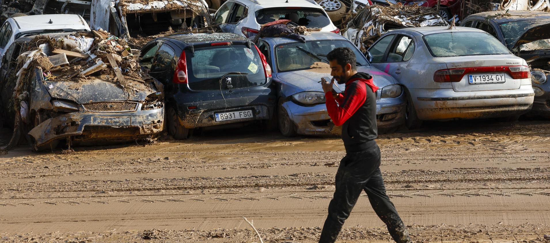 Un hombre camina junto a los coches apilados en Catarroja, Valencia.