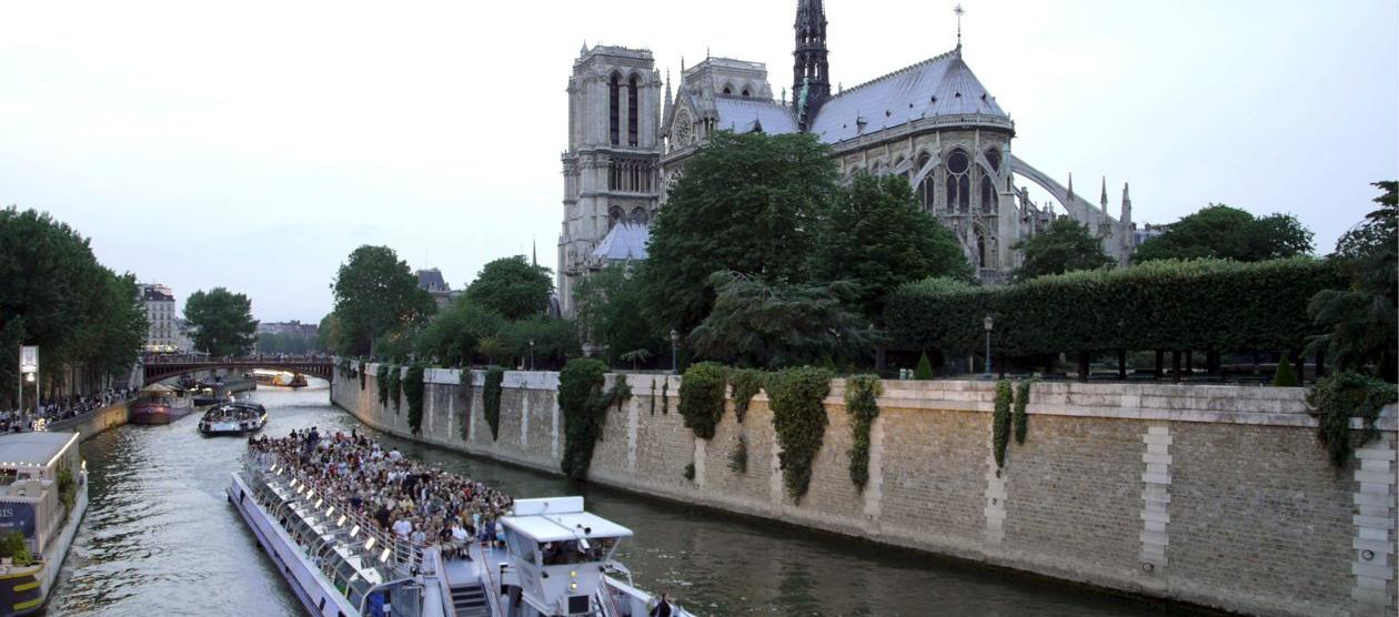 Un barco con turistas navegando por el Sena junto a la catedral de Notre Dame.