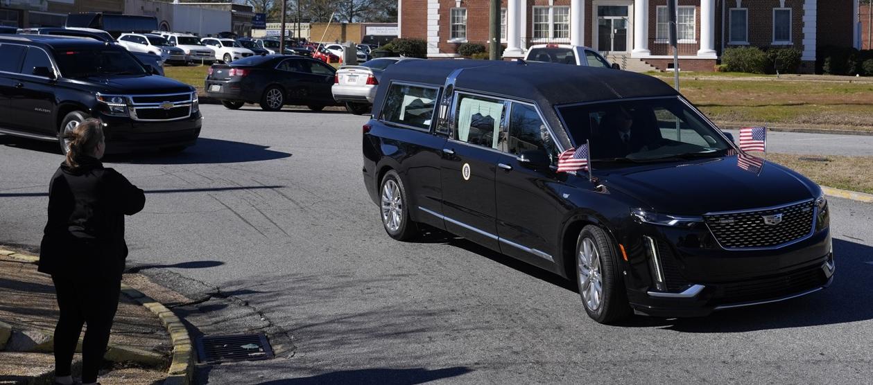 Las personas observan el paso del coche fúnebre.