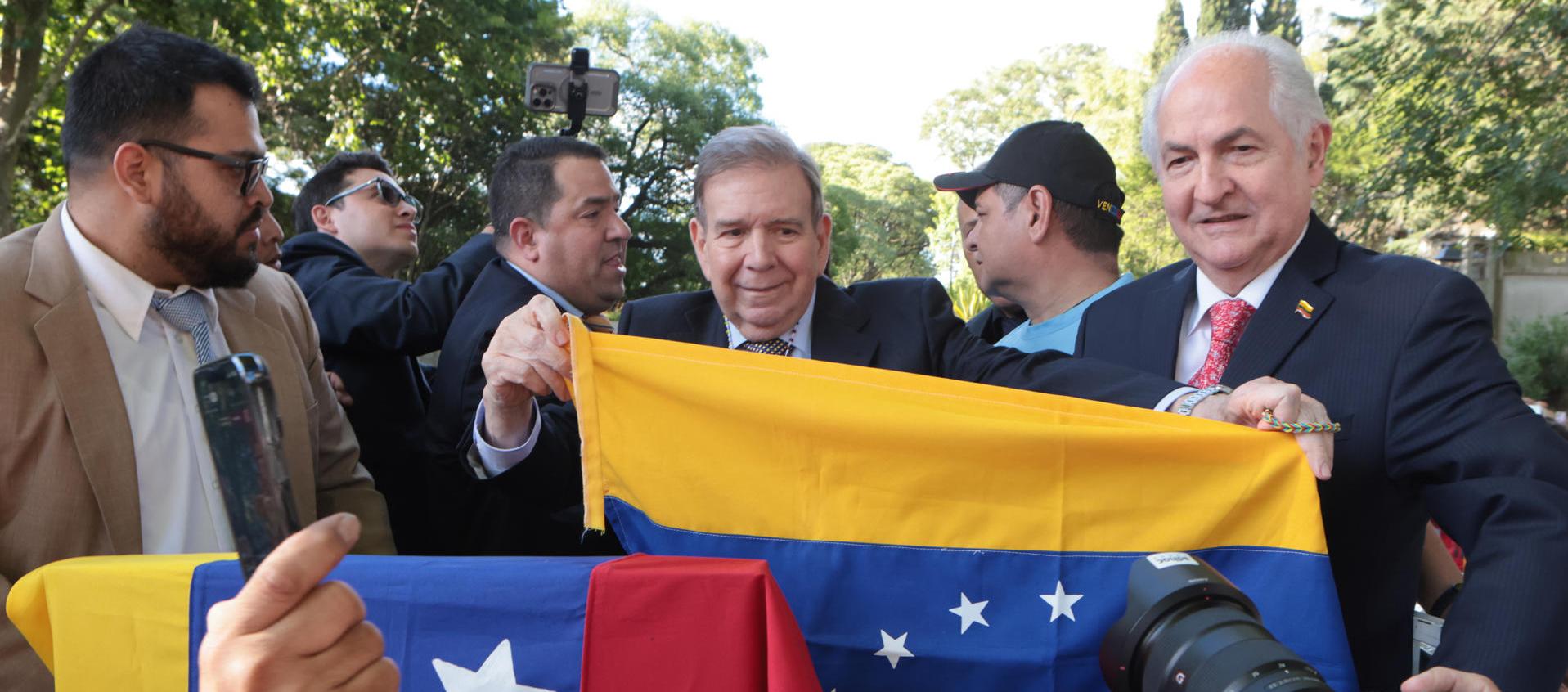Edmundo González sostiene la bandera de Venezuela en Montevideo, Uruguay.