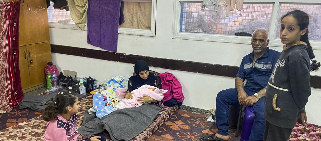 Imagen de una joven palestina refugiada junto a su bebé en una escuela de Rafah.