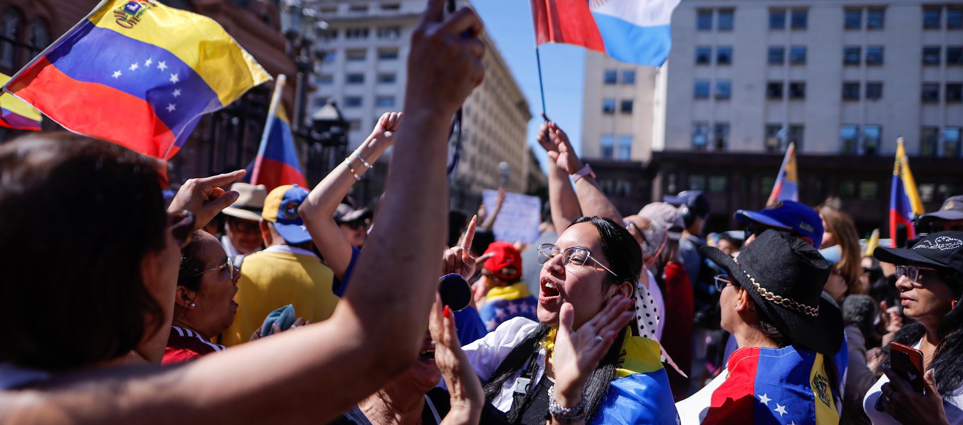 Personas agitan la bandera de Venezuela y gritan consignas este sábado en al Plaza de Mayo.