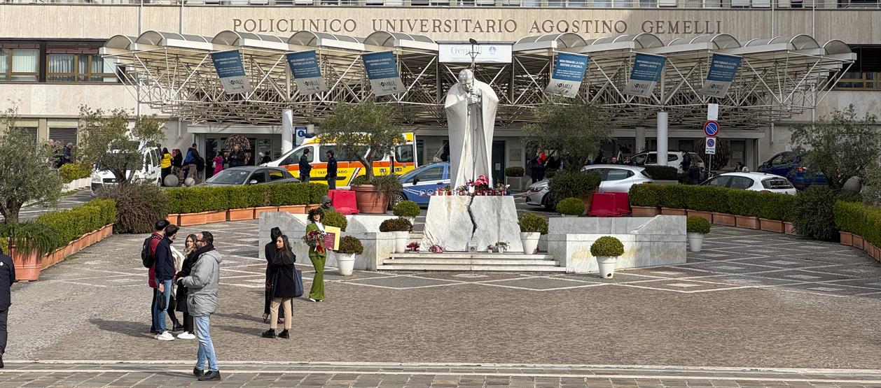 Velas y flores a los pies de la escultura de Juan Pablo II a las puertas del Hospital Gemelli