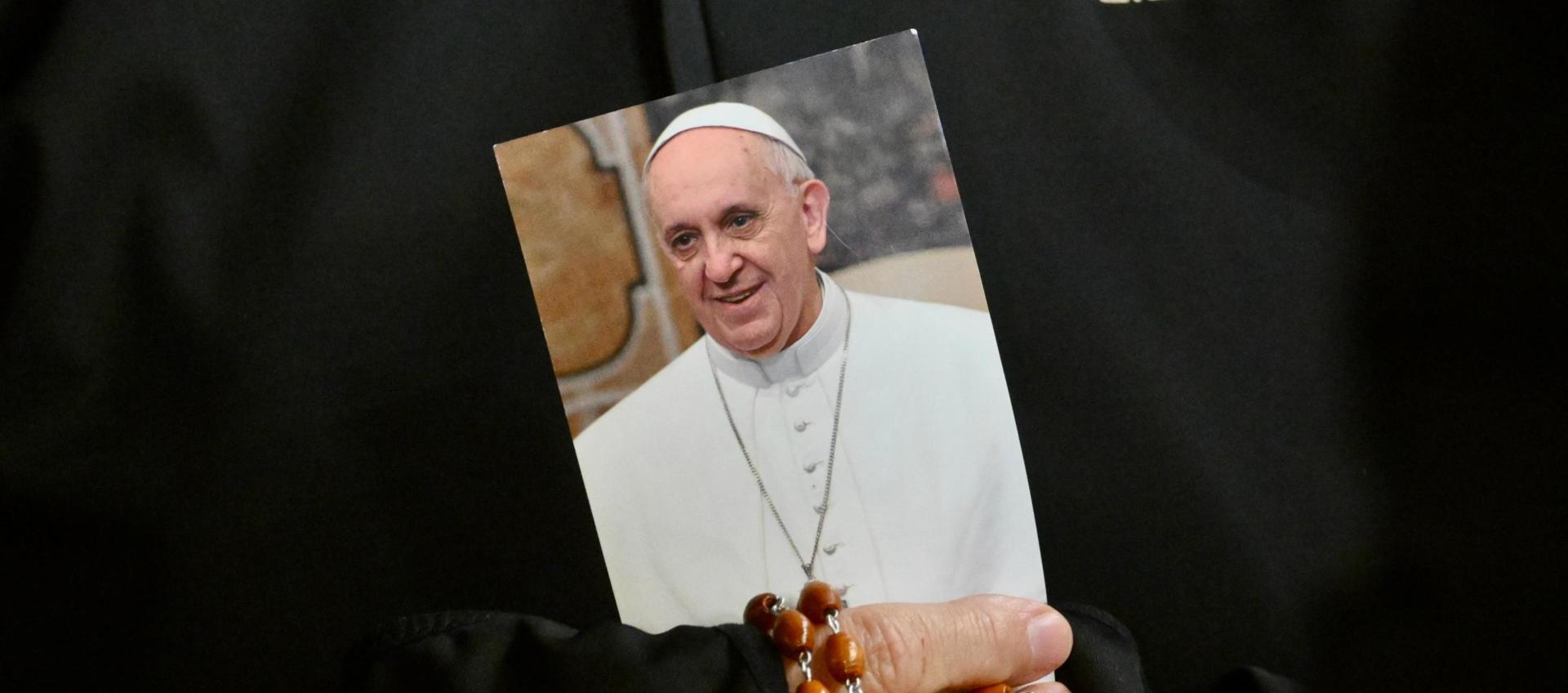 Una monja sostiene una imagen del Papa Francisco y un rosario.