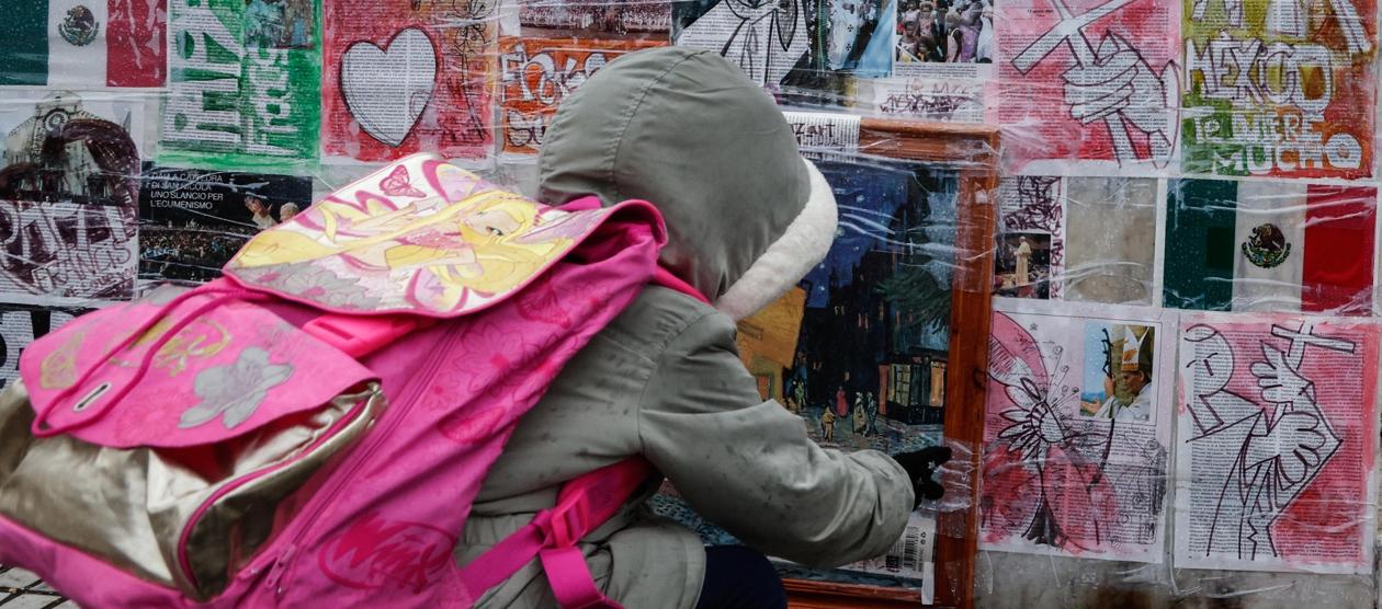 Un niño mira dibujos y fotografías colocadas en la parte inferior de la estatua de Juan Pablo II junto al Hospital Gemelli.