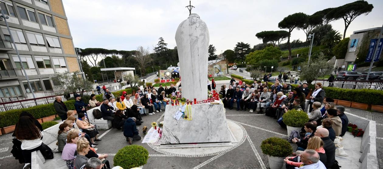 Un grupo de peregrinos rusos se reúne junto a la estatua de Juan Pablo II en la entrada del Hospital Gemelli.
