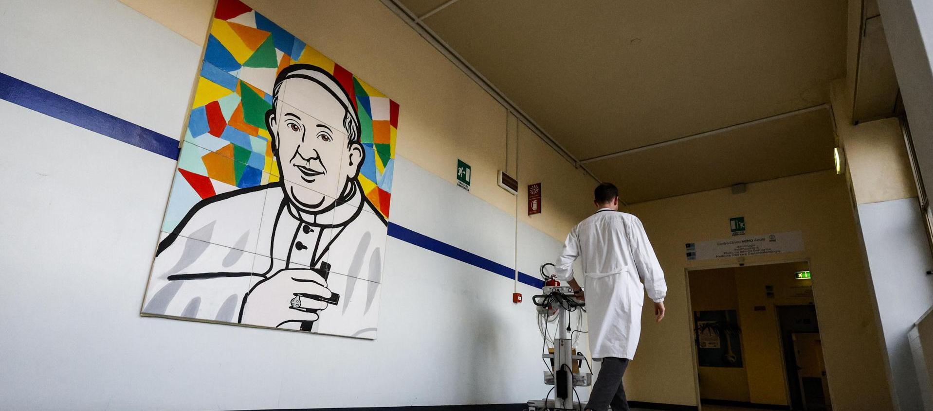 Un médico pasa junto a un mural que representa al Papa Francisco dentro del Hospital Gemelli.