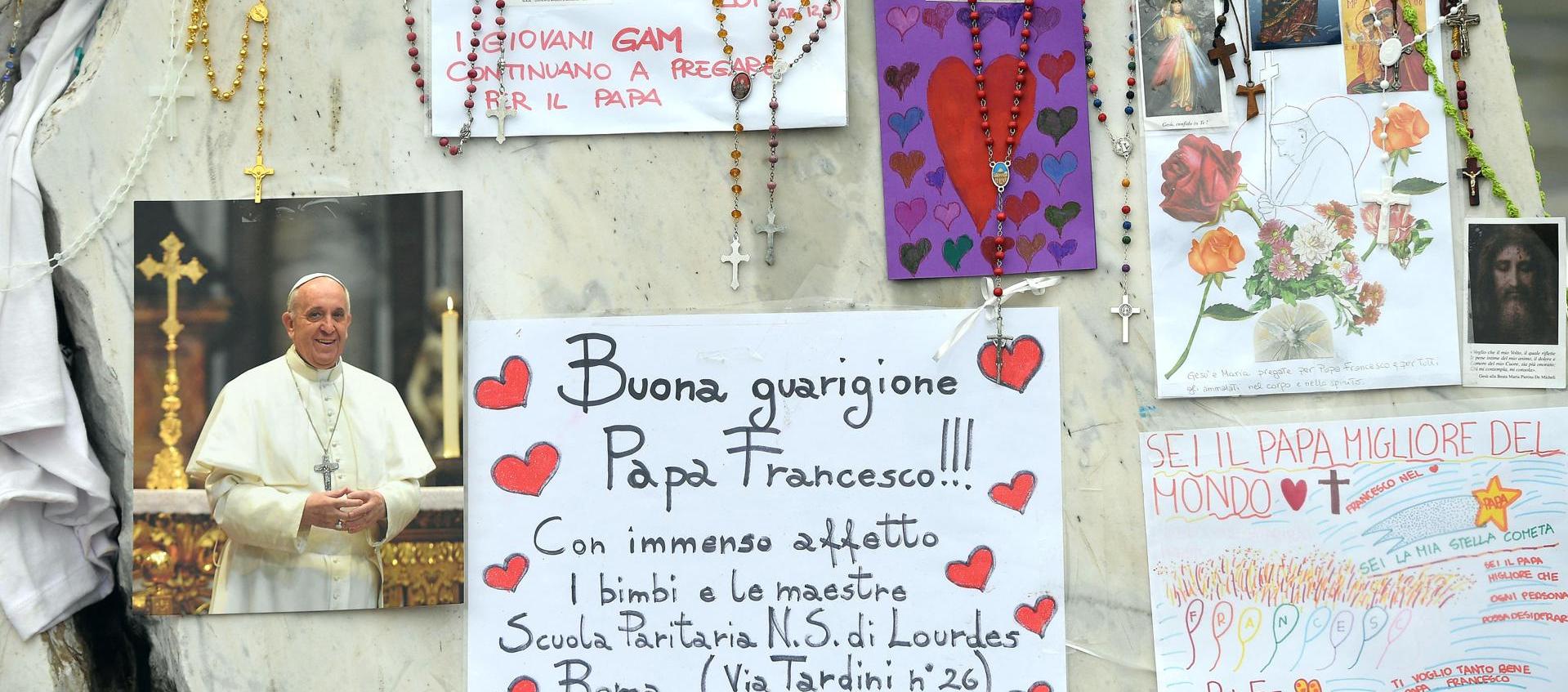 Velas, rosarios y mensajes de apoyo al Papa Francisco se exhiben en la estatua del papa Juan Pablo II junto al Hospital Universitario Gemelli, donde está hospitalizado.