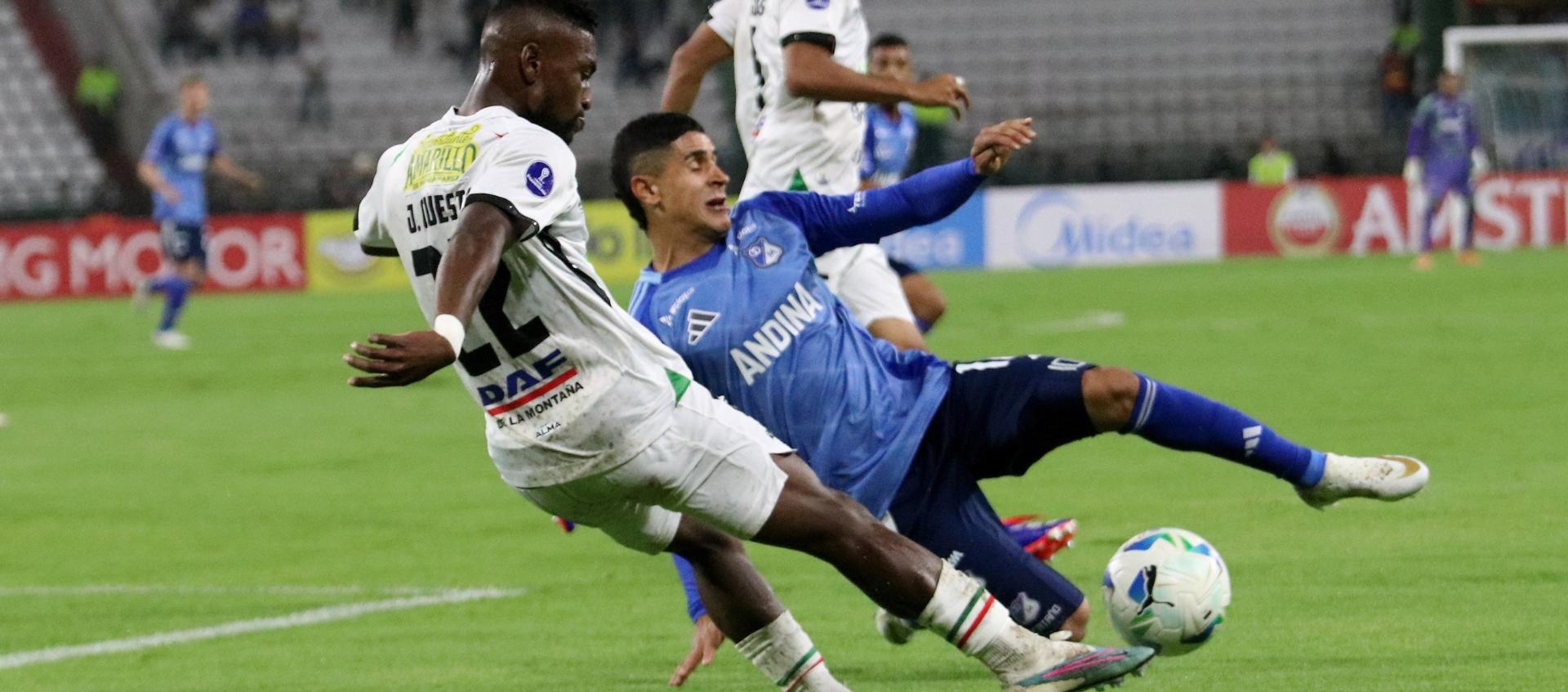 Juan David Cuesta intenta despejar ante la marca de Daniel Cataño. 