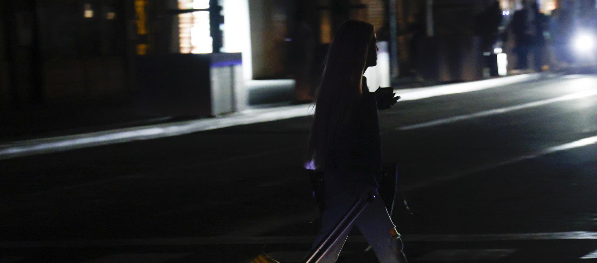 Una joven transita por una calle en Barcelona durante el apagón.