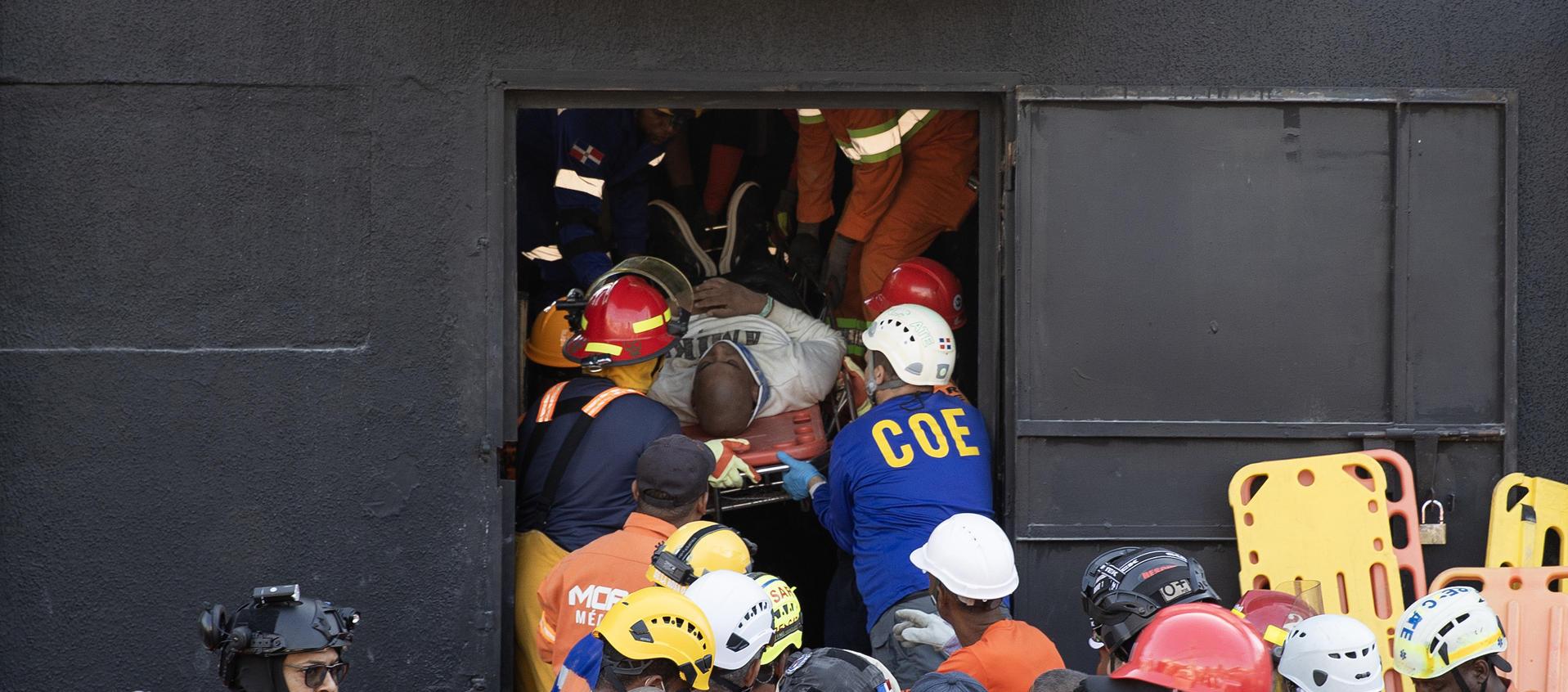 Integrantes del cuerpo de bomberos y de rescate evacuan a un herido este martes, en la discoteca Jet Set en Santo Domingo.