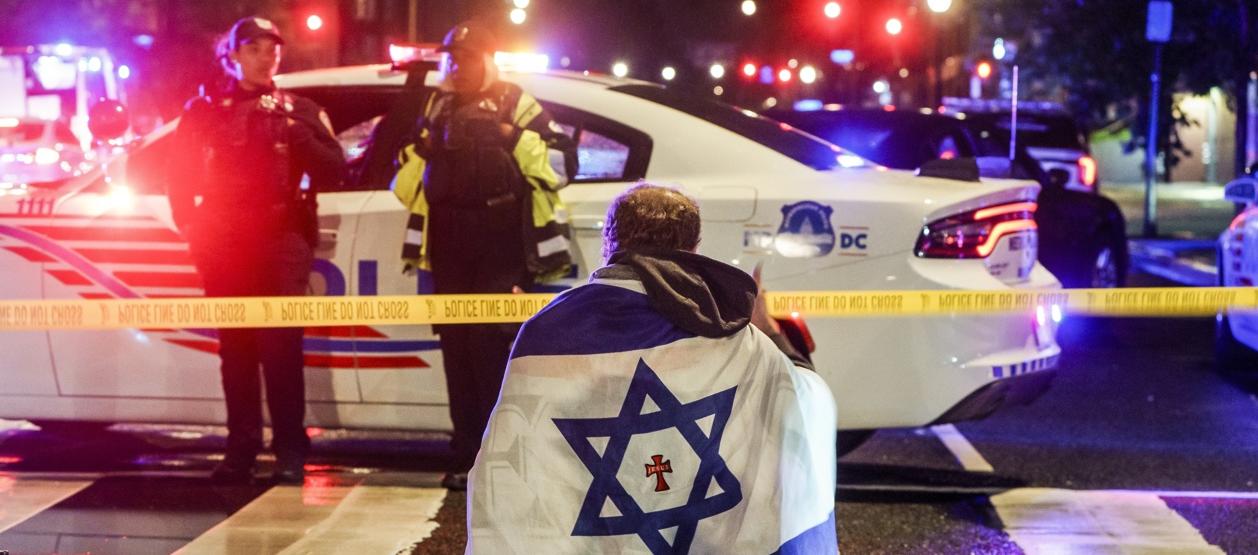 Un hombre con una bandera israelí en el lugar de los hechos.