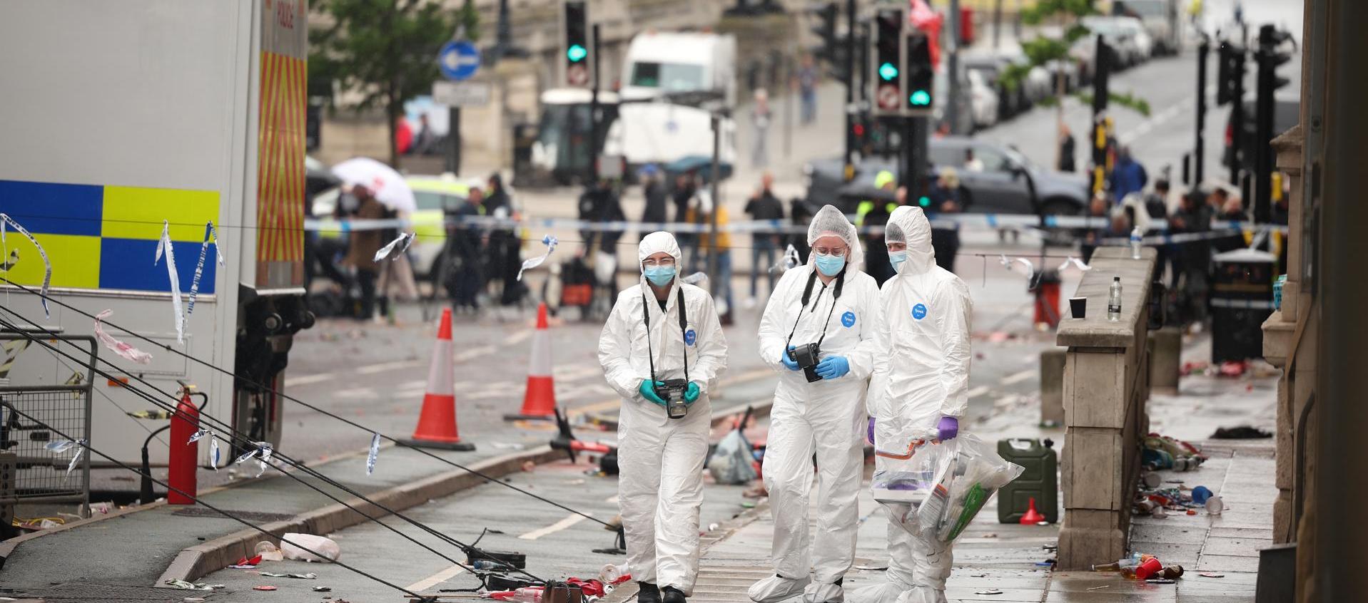 Oficiales forenses en el lugar donde un carro colisionó con personas durante el desfile del trofeo del Liverpool FC.