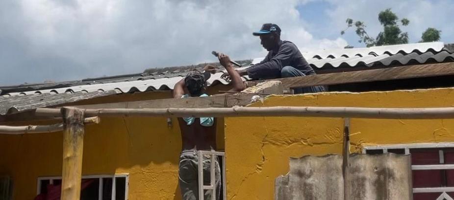Dos personas aseguran el techo de sus viviendas. 