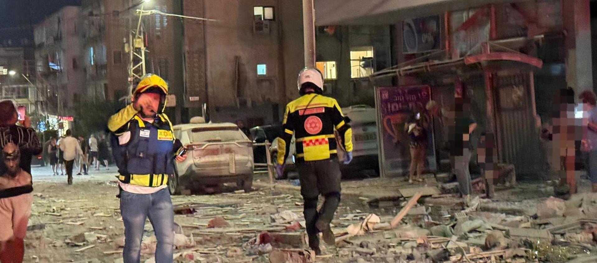 Integrantes de equipos de emergencia, bomberos y policía, trabajan en el área donde un proyectil iraní.