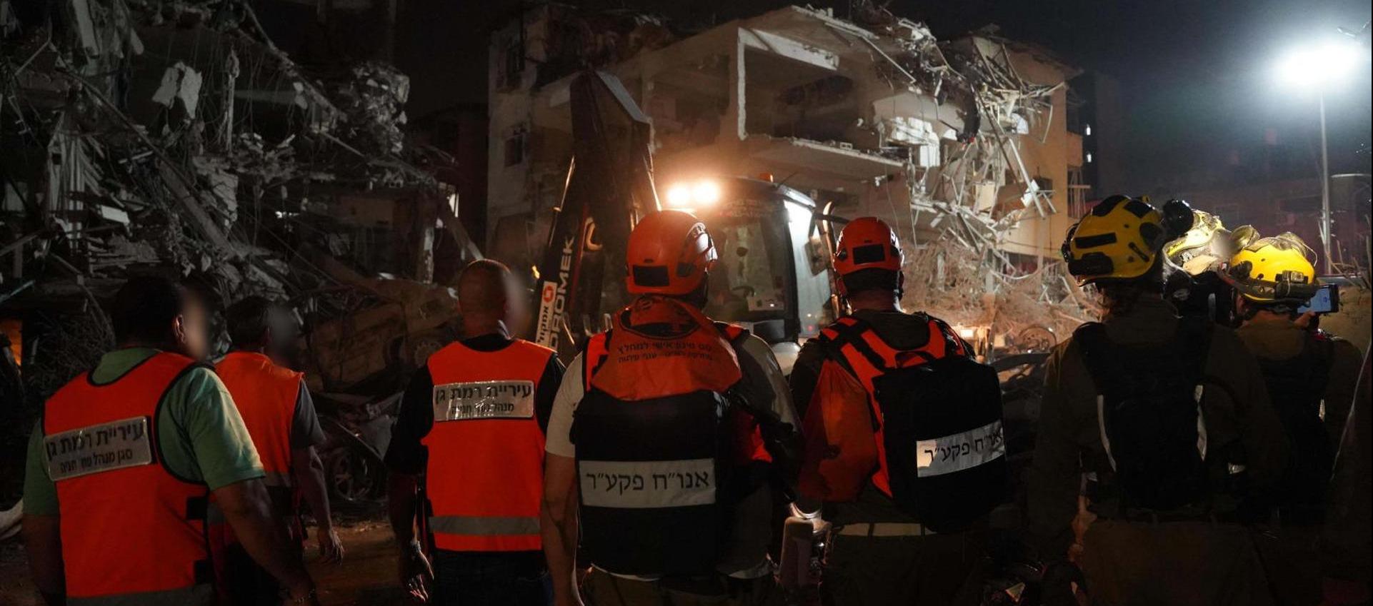 Integrantes de los cuerpos de emergencia junto a un edificio destruido por un misil iraní en Tel Aviv.