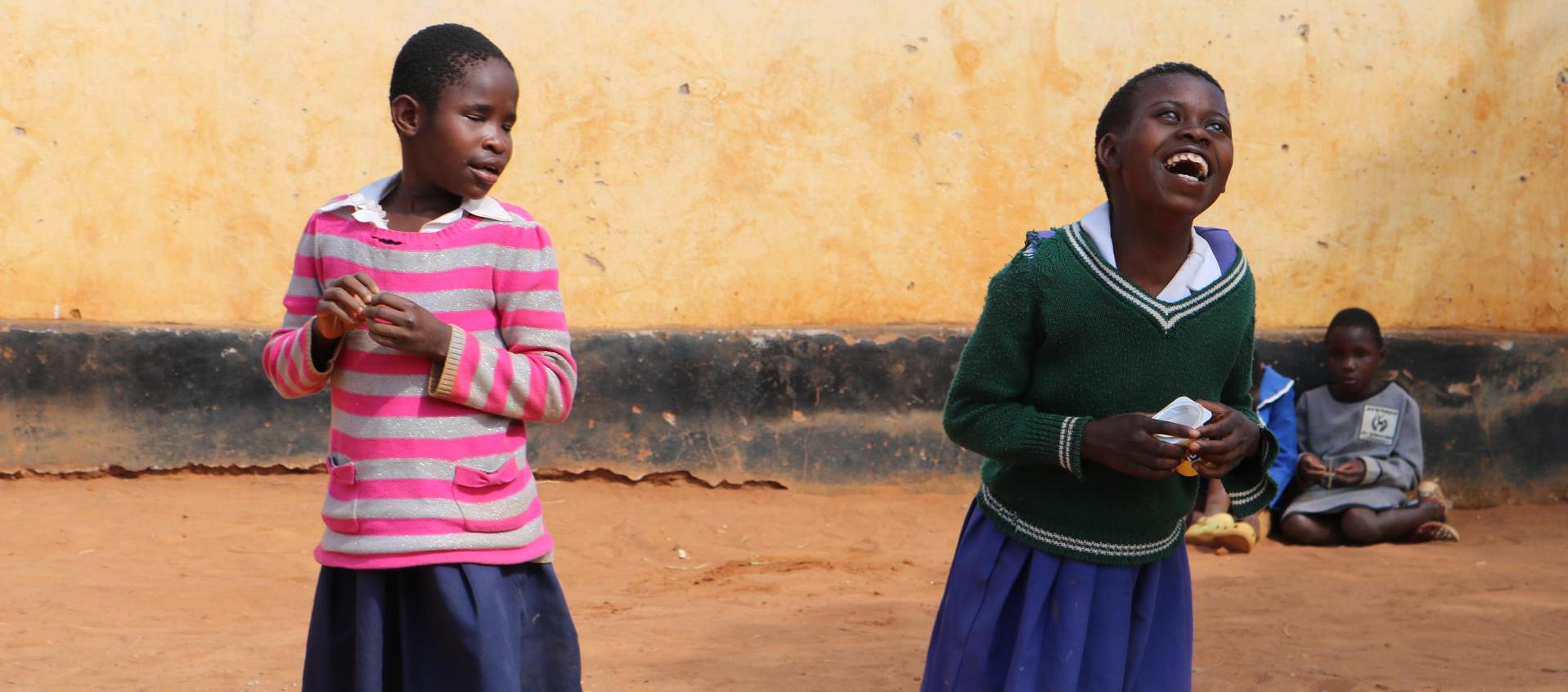 Dos estudiantes con discapacidad visual juegan y ríen durante el recreo.