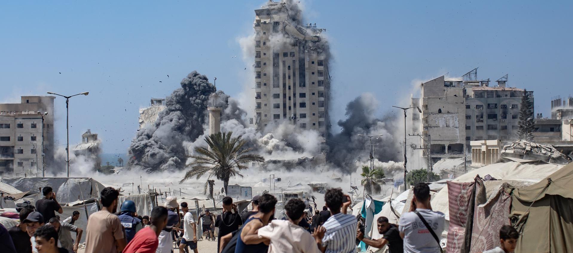 Ciudadanos palestinos reaccionan al humo que se eleva desde la Torre Mushtaha tras un ataque aéreo israelí.