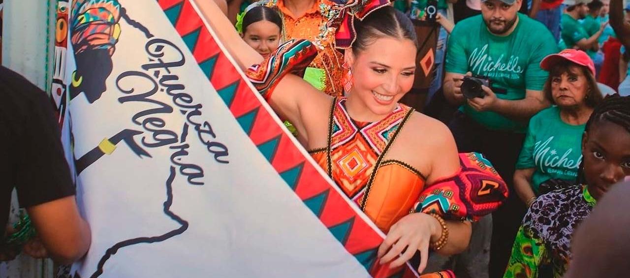 La Reina Michelle izando la bandera del grupo 'Fuera negra'.  