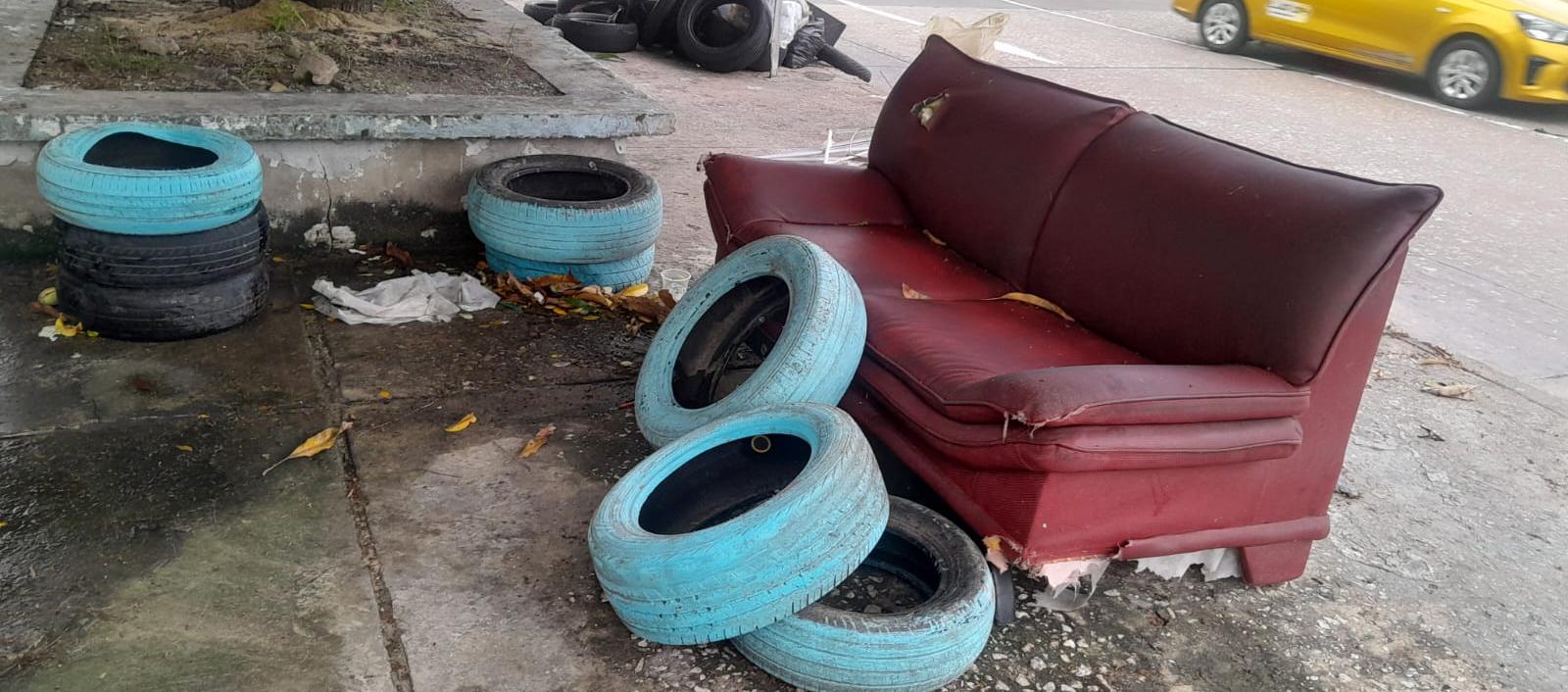 Llantas y un sofá abandonado frente al colegio. 