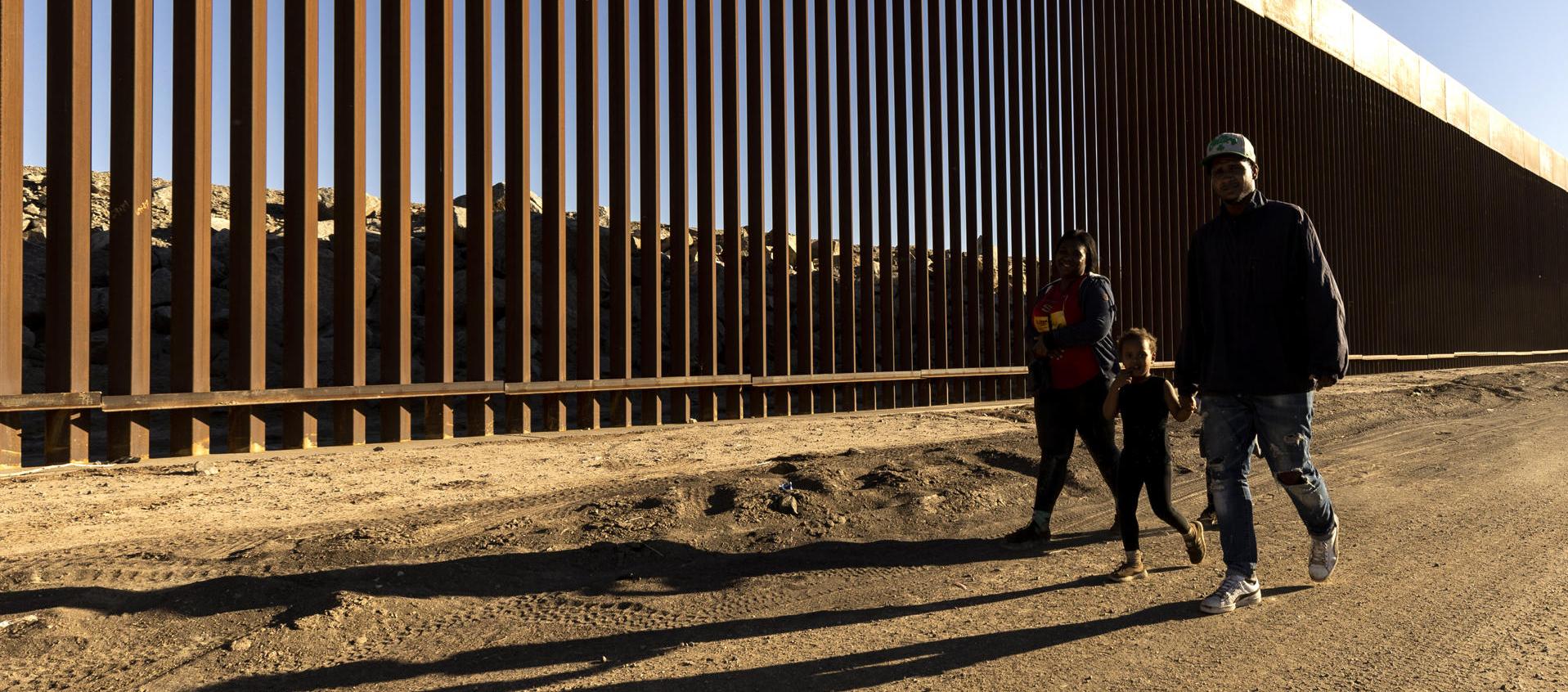 Familia caminando junto al muro fronterizo en Yuma, Arizona.