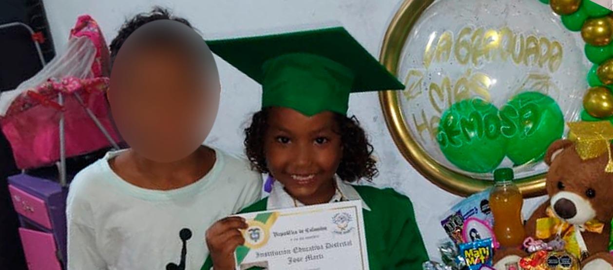 La niña con su diploma de grado y al lado de su hermanito.
