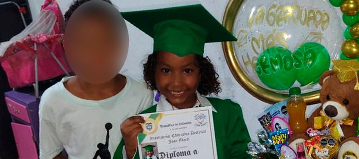 La niña con su diploma de grado y al lado de su hermanito