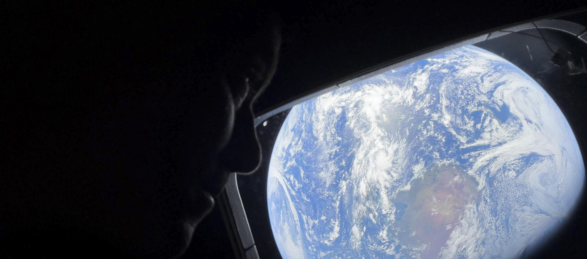 El comandante Reid Wiseman observa la Tierra mientras continúan adentrándose en el espacio hacia la Luna.