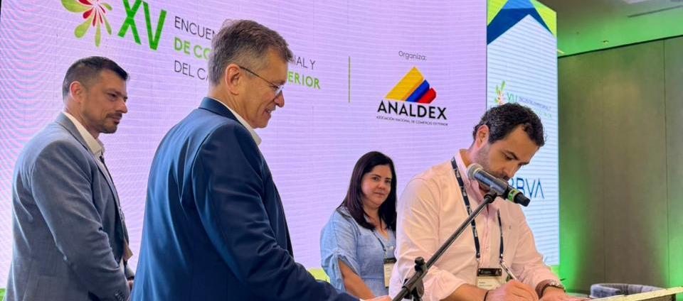 Hebert Mantilla, director de Comfamiliar Atlántico, firmando el convenio. A su lado, Javier Díaz, de Analdex.
