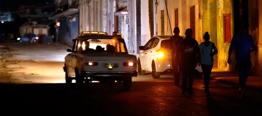 Personas caminan por un sector sin servicio eléctrico en La Habana. 