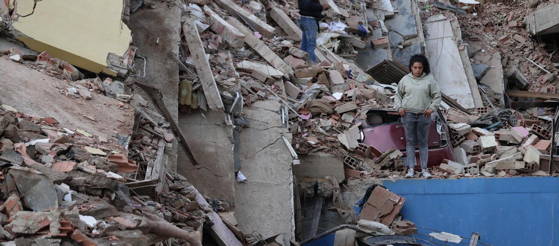 Residentes caminan entre los escombros de edificios derrumbados por los terremotos, en la localidad de Catia La Mar, en La Guaira.