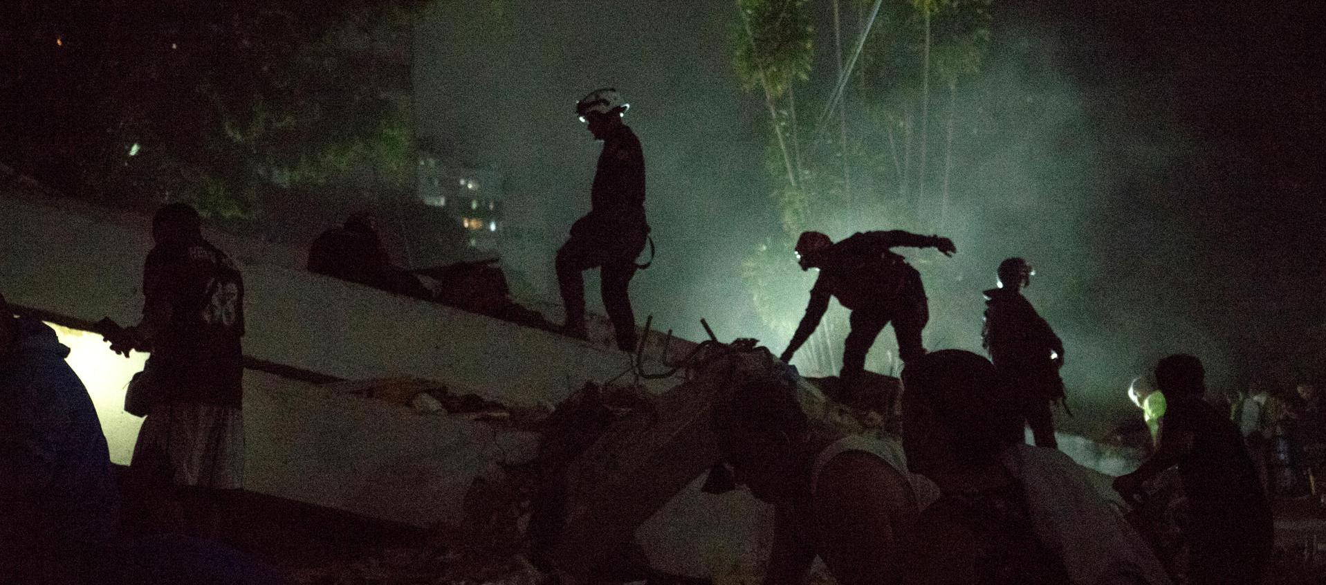  Integrantes de cuerpos de emergencia buscan víctimas entre escombros