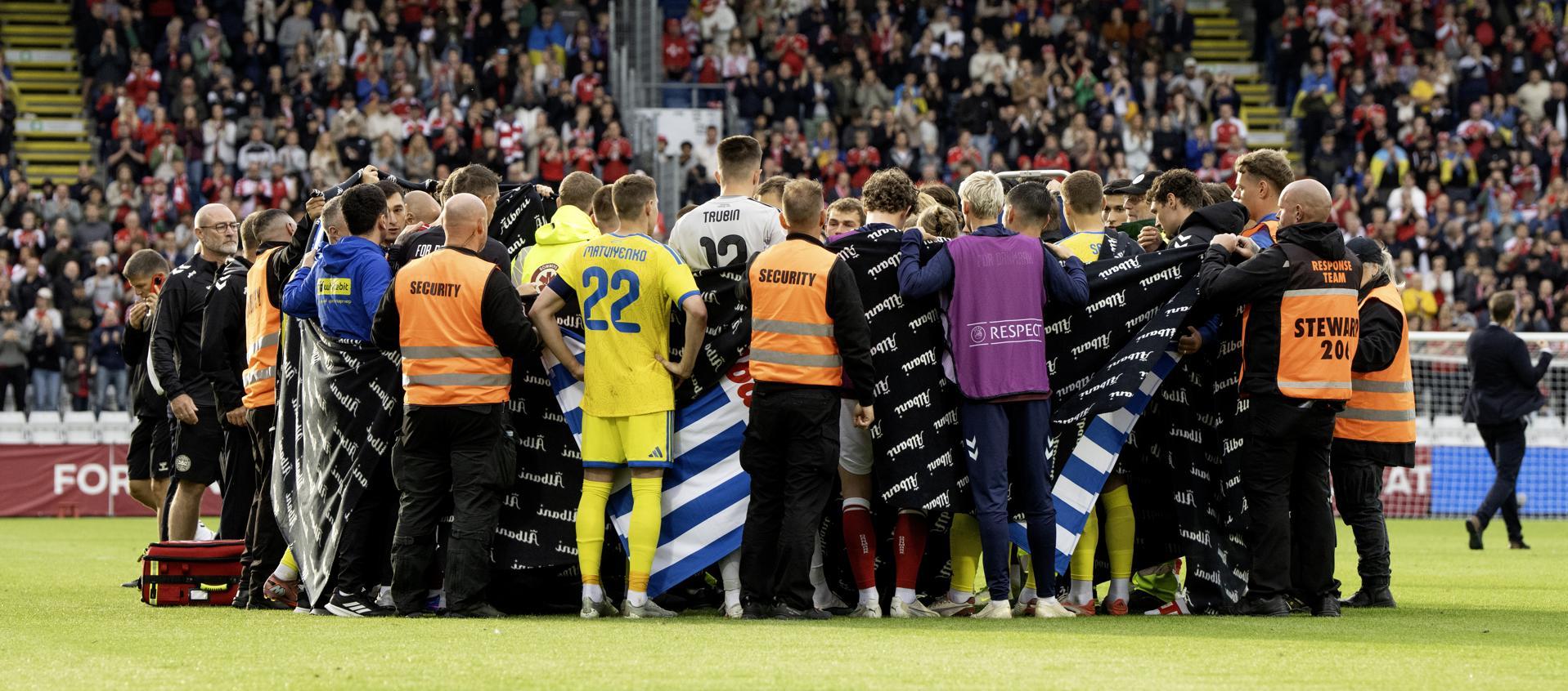 Jugadores de Dinamarca y Ucrania alrededor de Christian Eriksen después de que se desplomara.