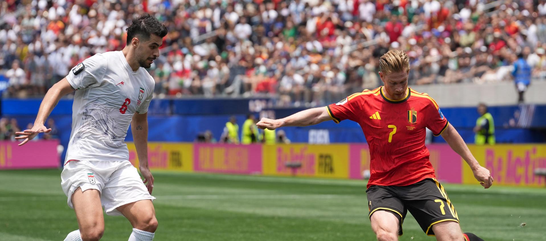 Kevin De Bruyne, de Bélgica, disputa el balón con Saeid Ezatolahi, de Irán.