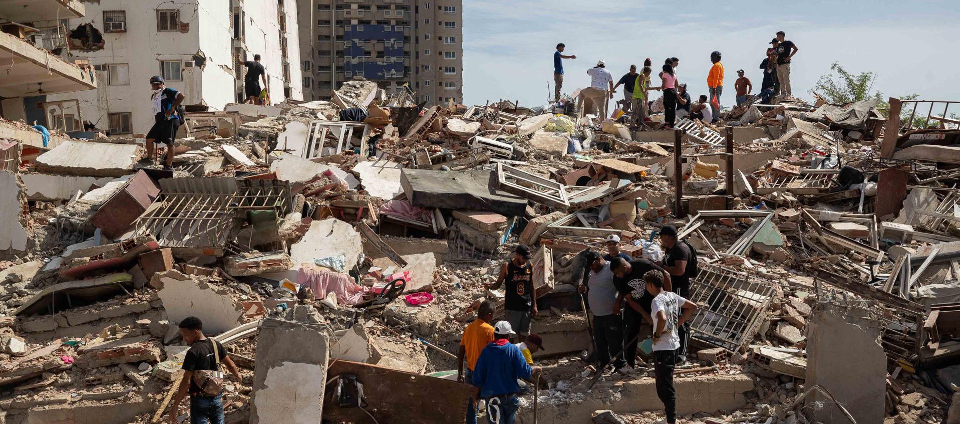 Personas caminan entre escombros de edificios afectado por terremotos