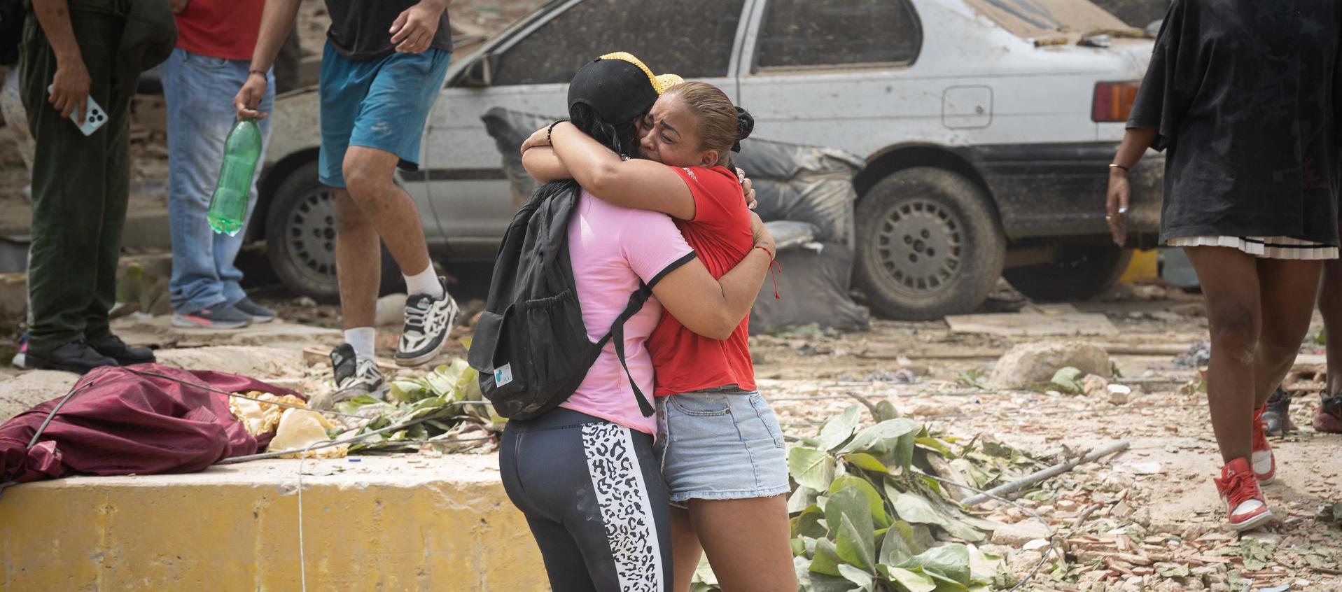 Personas lloran frente a escombros de edificios afectados por los terremotos 