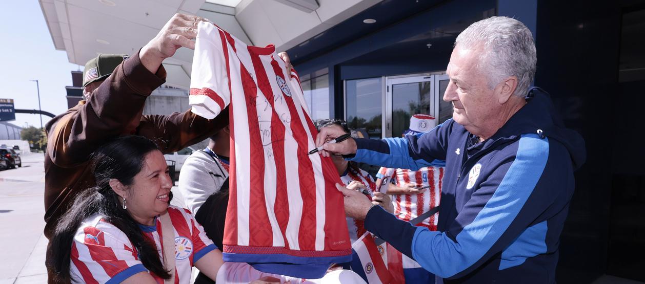 Gustavo Alfaro, técnico de Paraguay, firma camisetas a los aficionados.
